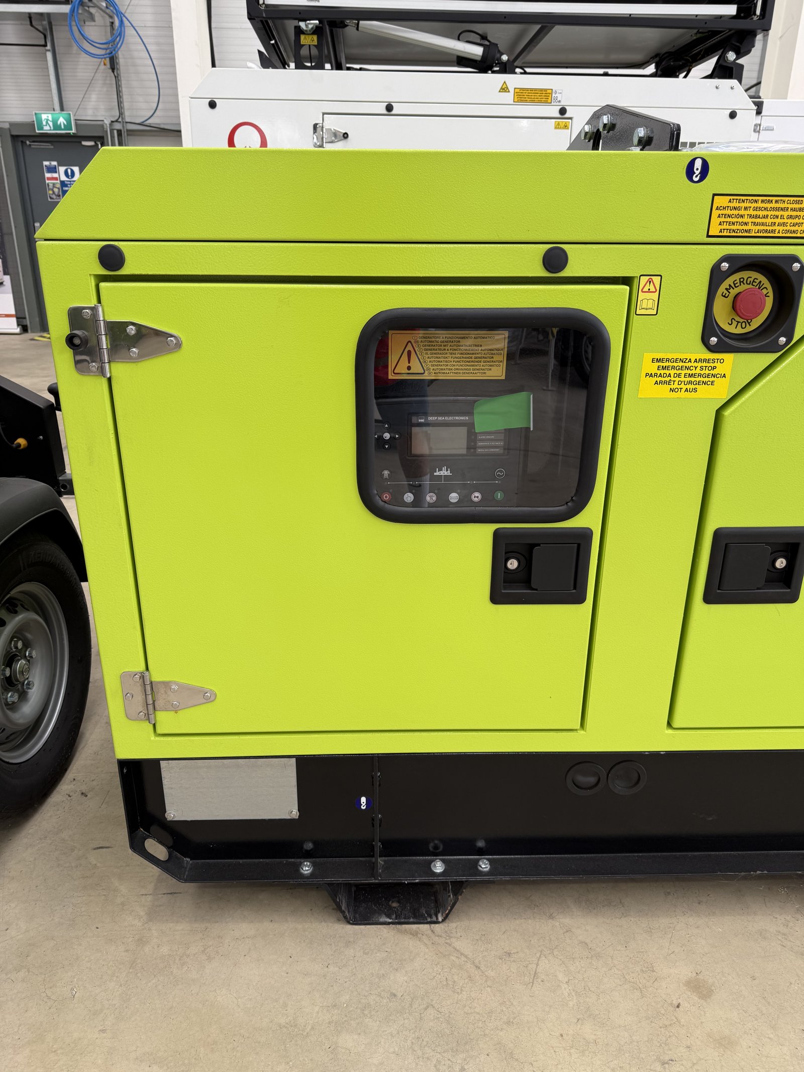 Front view of a PRAMAC silent diesel generator in a lime green weatherproof acoustic canopy. The generator features a digital control panel behind a viewing window, lockable access doors, eme