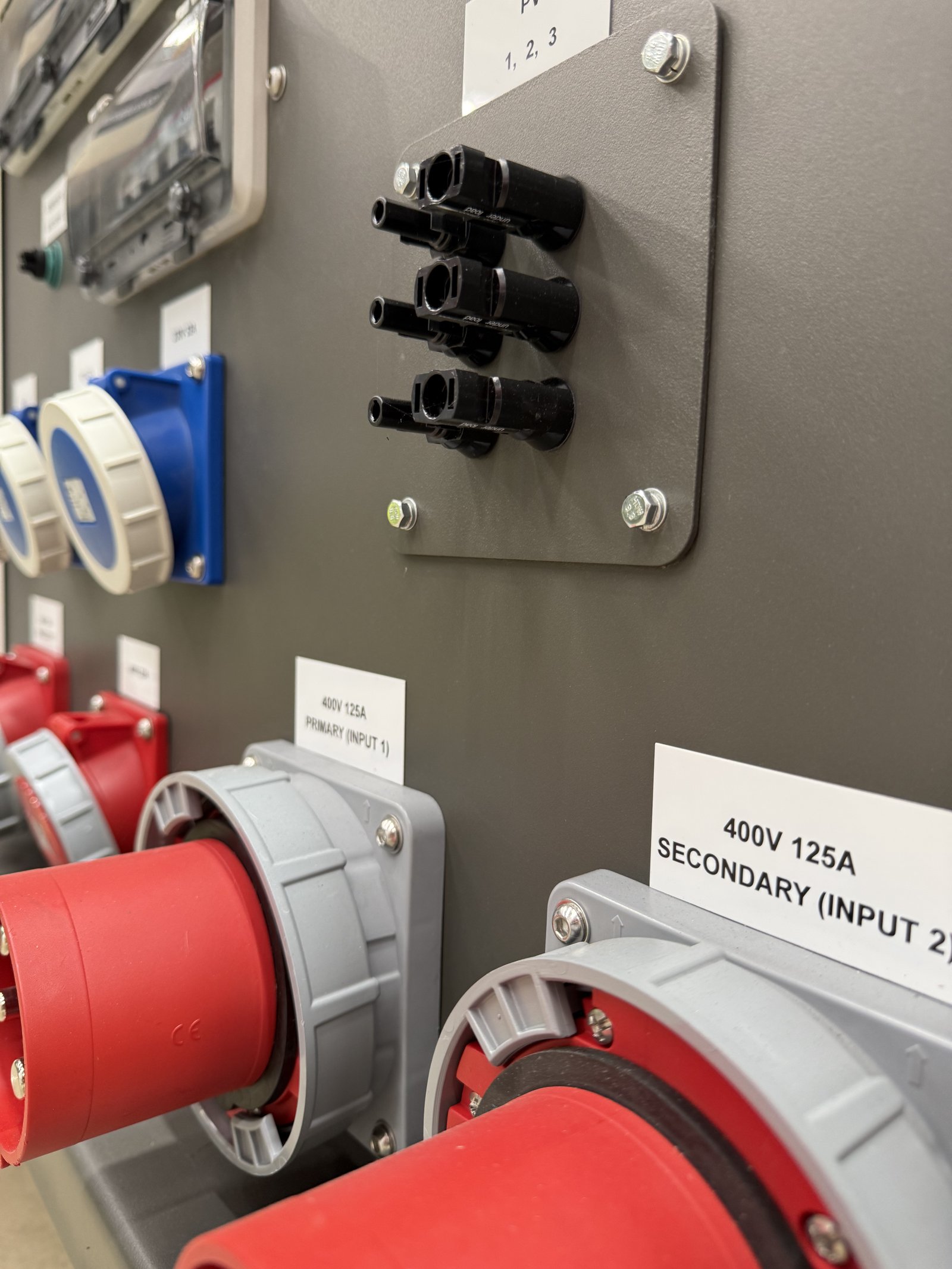 Close-up of an industrial generator power distribution panel featuring 400V 125A three-phase input connectors, industrial CEE sockets, and generator paralleling connection ports. The heavy-du