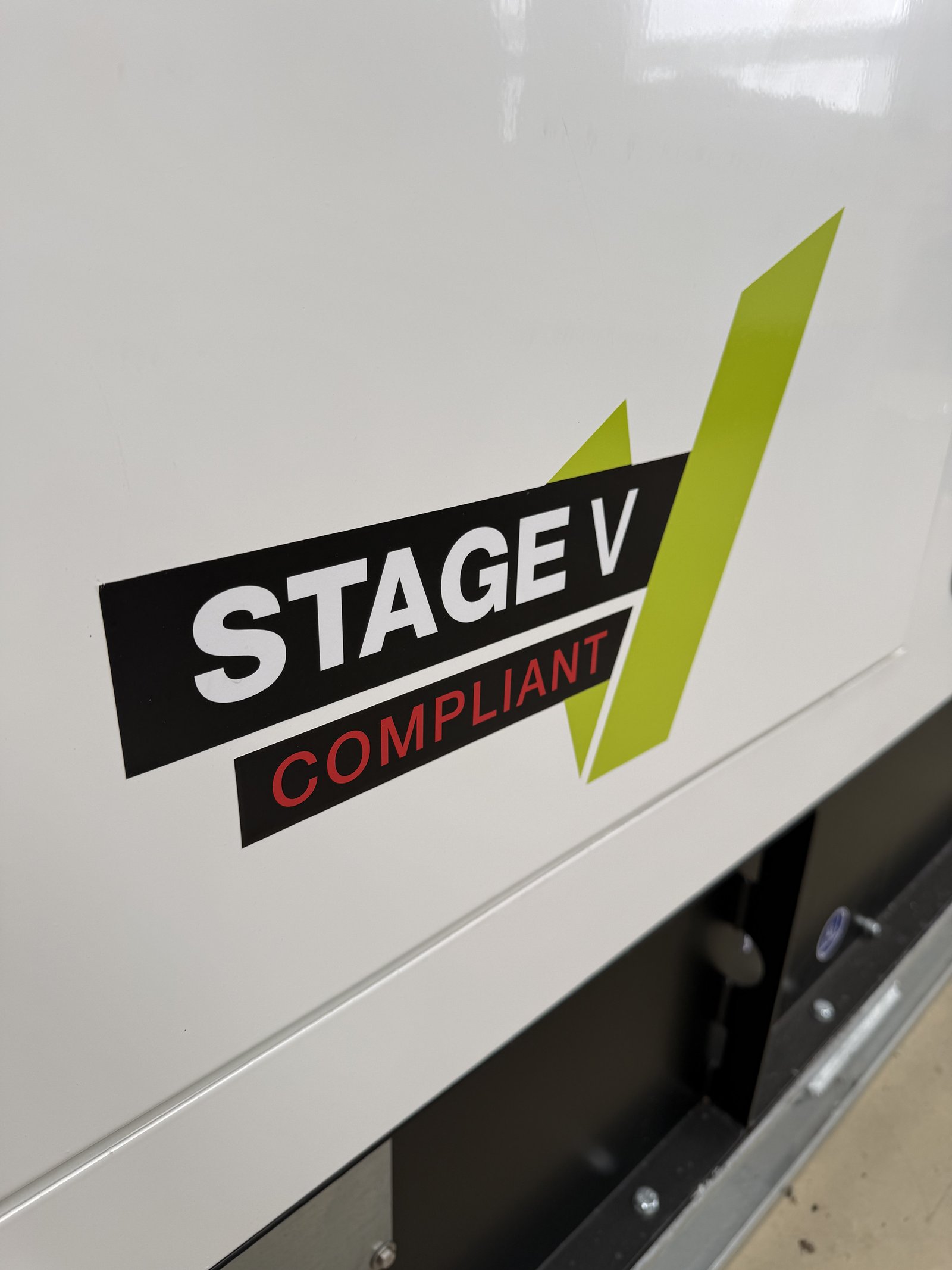 Close-up of a Stage V Compliant badge displayed on the acoustic canopy of a PRAMAC silent diesel generator. The label highlights compliance with the latest EU Stage V emissions regulations, e